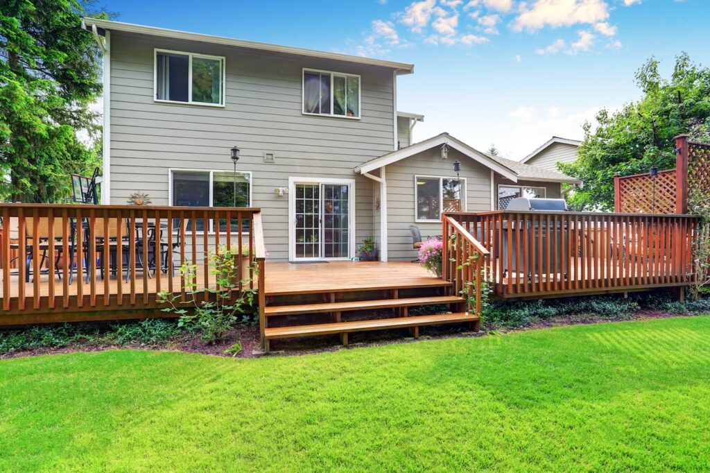 Back yard house exterior with spacious wooden deck with patio area and attached