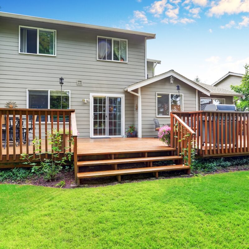 Back yard house exterior with spacious wooden deck with patio area and attached